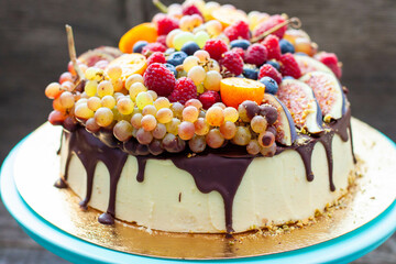 Wall Mural - Delicious cheesecake with melted chocolate, apples, strawberries, blueberries, peaches, raspberries, blueberries, figs and grape on the top