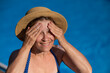 Portrait of an older woman applying sunscreen to her face while on vacation. 