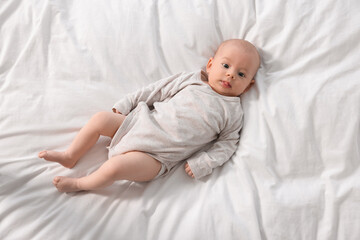 Sticker - Cute little baby lying on white sheets, top view