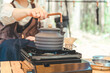 キャンプでコンロとケトルを使ってお湯を沸かしコーヒーを淹れる女性キャンパーの手元
