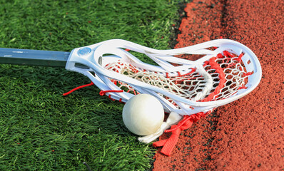 Wall Mural - Lacrosse stick on the turf next to a ball close to the track