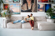 Peaceful couple spouses artists relax in house studio. Smiling man, woman hugging while sitting, lying on sofa among picture composition on wall. Boyfriend girlfriend resting together on couch.