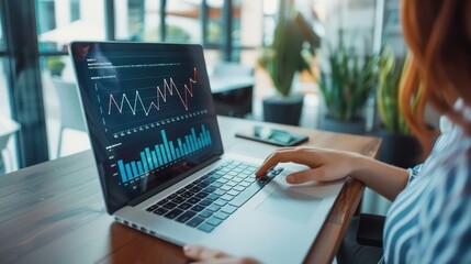 a female accountant working on a laptop in a modern office space, with graphs and charts displayed o