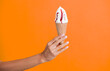 Gelato ice cream cone. Ice cream cone isolated on orange. Summer vanilla taste. Woman holding the ice cream by hand. Ice cream in hand. Yummy summer gelato. Authentic Italian gelato