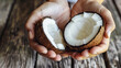 Close-up of male hands holding halved coconut on the wooden table