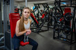 Young woman posing with dumbbells in her hands and works out in the gym performing an exercise