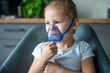 Cute little girl are sitting and holding a nebulizer mask leaning against the face, airway treatment concept
