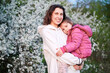 Woman and child allergic enjoying after treatment from seasonal allergy at spring. Happy mother holding young daughter smiling in front of blossom tree at springtime. Spring allergy concept.