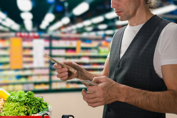 Wall Mural - Male client paying by cash money in dollar banknotes for food products. Cash payment: Dollars exchanged at the supermarket checkout for goods