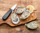 Fototapeta  - Three opened raw oysters and oyster knife on wooden table. Top view.
