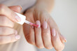 Nail Care And Manicure. Closeup Of Beautiful Female Hands Applying Transparent Nail Polish On Healthy Natural Woman's Nails
