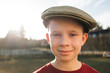 © Cavan Images - boy stood outside at sunset with a flat cap