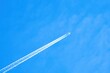 Airplane with contrails in the blue sky.