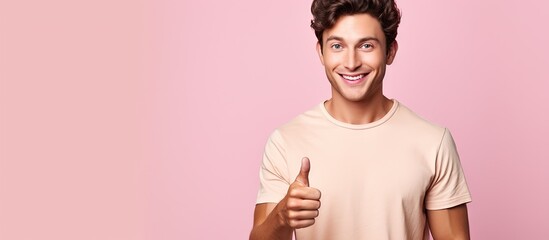 A smiling young man wearing a brown shirt confidently points towards something good inviting your attention The pink background adds a pleasing contrast with ample copy space for your advertisement E