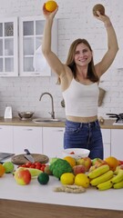 Canvas Print - Beautiful slim woman is dancing with fresh fruits in the modern kitchen. Happy woman holding coconut and orange having fun at home. Organic fruit and vegetables. Dieting concept. Vertical video