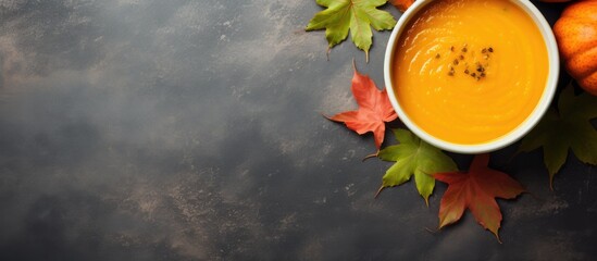 Wall Mural - a top view of a frame of pumpkin puree soup with autumn leaves set against a grey background of pump