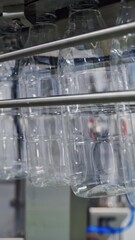 Wall Mural - Pure transparent bottles on a conveyor belt. Conveyor with clean empty bottles at big factory. Plastic bottles moving on manufacturing line in a modernized plant. Vertical video