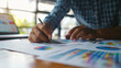 © OMD - Professional at work analyzing financial statistics displayed on charts and graphs, using a pen for notes