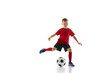 Dynamic shot of little boy in sports uniform plays football, training passing ball against white studio background. Concept of professional sport, championship, youth league, hobby. Ad