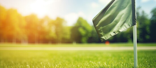 Sunny summer day with green football field trees in the background and a vibrant orange corner flag waving on the fresh grass Copy space image