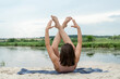 Beautiful young slim woman in sportwear practicing yoga pose by the lake