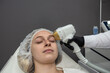 young woman lies in spa center and receives laser hair removal procedure