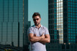 Stylish man wearing sunglasses and shirt. Handsome man outdoors portrait. Portrait of stylish male model outdoor. Fashion male posing near skyscraper on the street. Fashionable man in urban style.