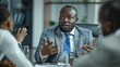 © Sittipol  - A black man in a suit and tie is having a serious conversation with two other people in a business setting.