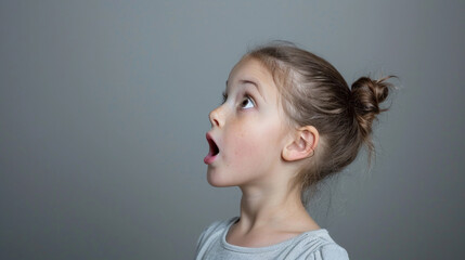 Wall Mural - a girl with a ponytail surprised on a gray background