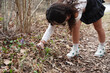 A teenage girl takes pictures of Hepatica nobilis flowers in a spring forest on a smartphone..
