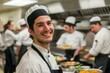 Happy male chef wearing uniform stands out in a busy commercial kitchen
