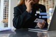 Businesswoman with a credit card in hand talking on mobile phone at her office desk