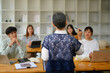 Rear view of senior professor talking to students during lecture in the classroom