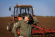 Portrait of farmer standing in field preparing to cultivate the land with a tractor.