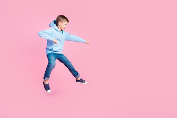 Wall Mural - Full body profile photo of active little boy jump hit fight empty space isolated on pink color background