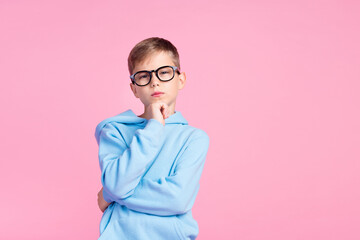 Wall Mural - Portrait of minded intelligent schoolchild hand touch chin contemplate empty space isolated on pink color background