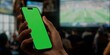 Smartphone with green screen in sports bar, perfect for app demos