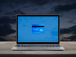 Credit card on modern laptop computer monitor screen on wooden table over sunset sky, Online e-payment concept, Elements of this image furnished by NASA