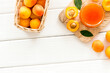 Summer preserves. Apricot jam in jar near fresh fruits on white wooden background top view frame copy space