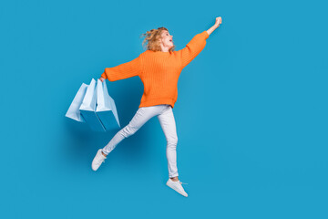 Wall Mural - Photo of crazy funny lovely woman wear trendy orange clothes hold packages fly empty space isolated on blue color background