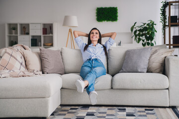 Poster - Full length portrait of pretty lady hands behind head sit sofa wear shirt bright interior apartment indoors