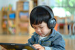 © igorfrost - asian preschool child using tablet with headphones, little kid watching cartoon, playing game or learning on a digital device, toddler screentime usage concept