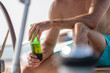 A Smart Caucasian male's hand is holding a green bottle of beer while enjoy his vacation or holiday party on a yacht or sailing, concept of drinks and alcohol promoted, commercial or advertisement.