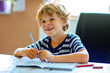 Portrait of happy boy doing homework in kitchen at home. Elementary school studing writing and learning. Smiling child.
