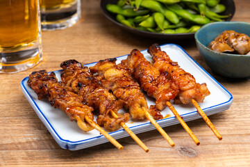 Poster - 居酒屋のテーブルに並んだ焼き鳥と料理とビール