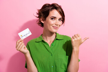 Sticker - Photo portrait of pretty young girl hold credit card point empty space dressed stylish green outfit isolated on pink color background