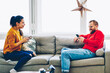 Happy hipster woman laughing and talking with her boyfriend sending her funny photos via smartphone, young romantic couple enjoying free time together share video using wireless internet at home