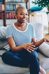 Wall Mural - Cheerful african american woman talking with female friend spending time together at apartment, multiracial hipster girls having conversation at home interior, female explaining emotional gesture