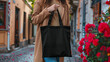 Close Up mockup of a woman holding a black blank tote bag.
