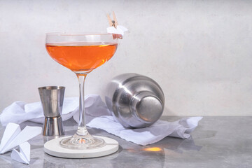 Wall Mural - Paper plane boozy alcohol cocktail with Bourbon, whiskey, amaro, aperol aperitif, fresh lemon juice and paper plane craft made decor, on white background with hard light and bar utensils